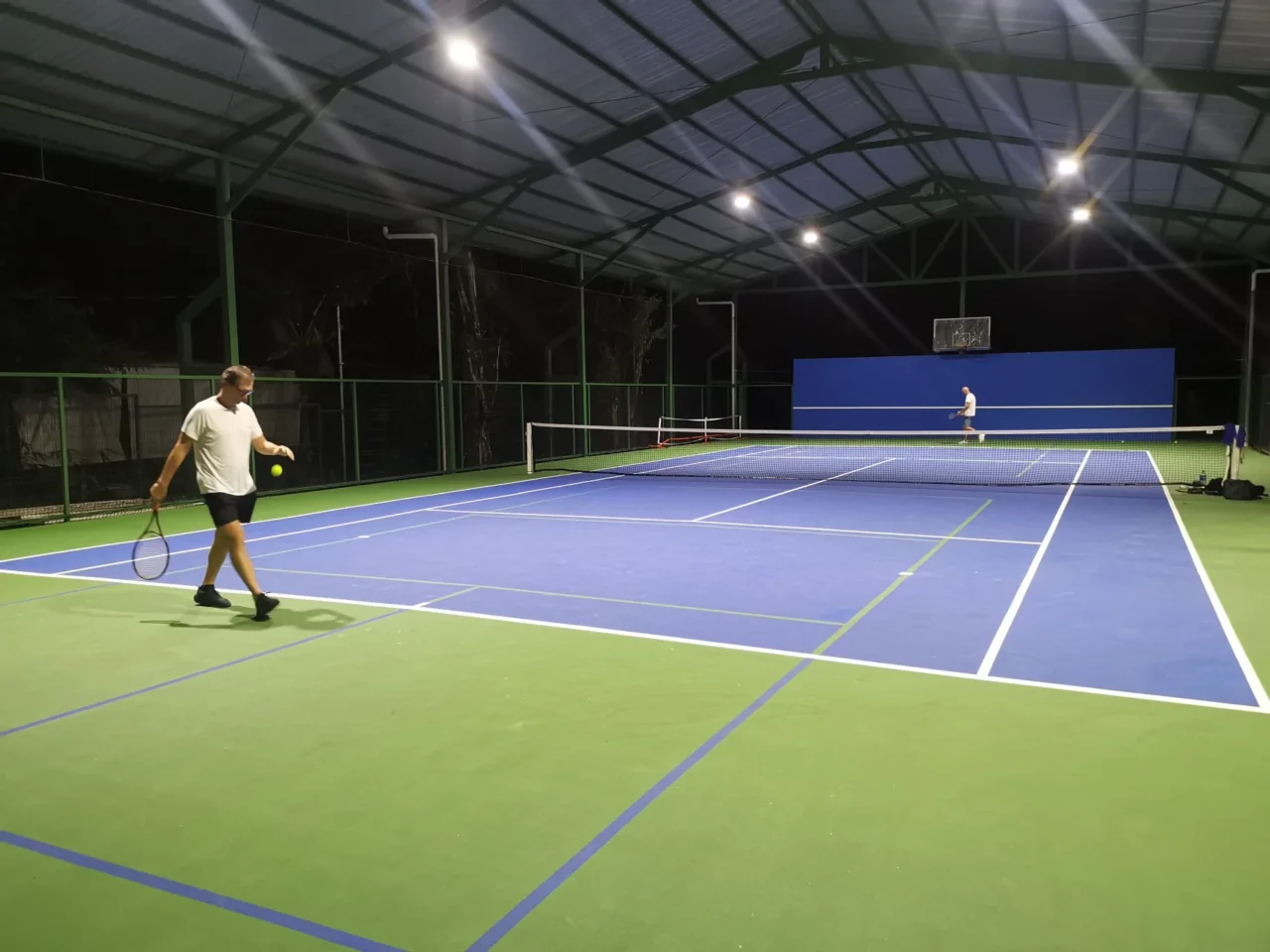 Two guests playing on a covered floodlit tennis court at the racquet club near Ojochal Gardens, Costa Rica